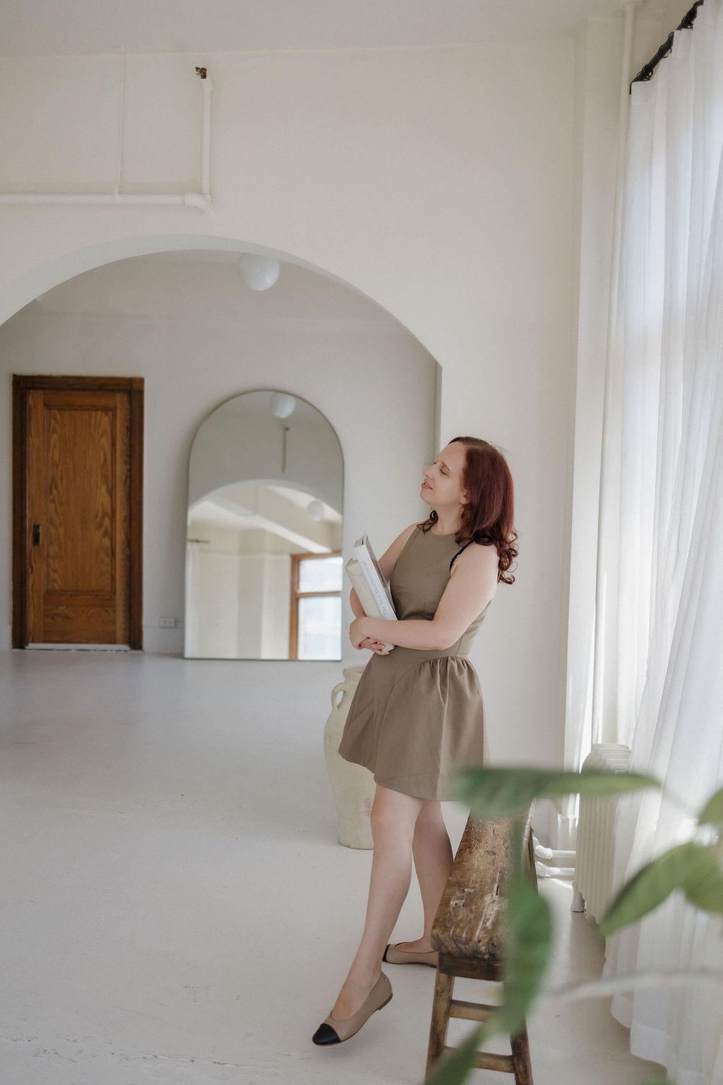 Kathleen standing in a sunlit hallway archway