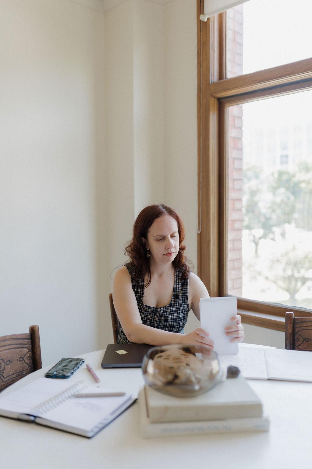 Kathleen working at a desk by a window
